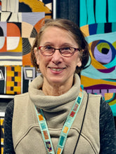 Load image into Gallery viewer, Woman with glasses standing in front of colorful abstract art
