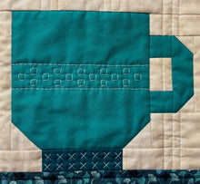 Load image into Gallery viewer, Teal mug design on a quilt with beige background
