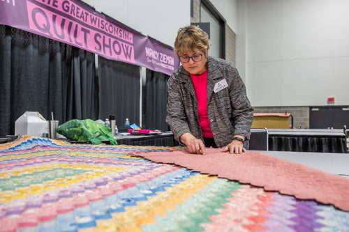 woman standing over quilt appraisal 