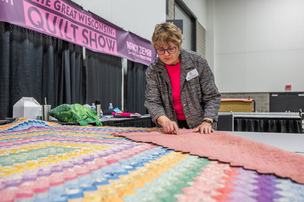 woman standing over quilt appraisal 