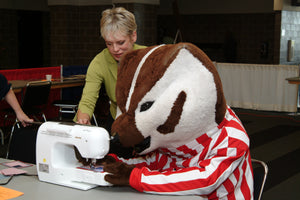 Nancy Zieman on a sewing machine with Bucky Badger