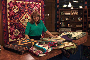 Nancy standing behind a table with a selection of quilts